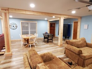A spacious living room with a wooden floor, a dining area with a table and chairs, and a sofa.