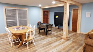 A room with a wooden table and chairs, a foosball table, and a black TV. - Peaceful Scenic Pond & Home Close to Beach/Sports/Entertainment (Elberta)