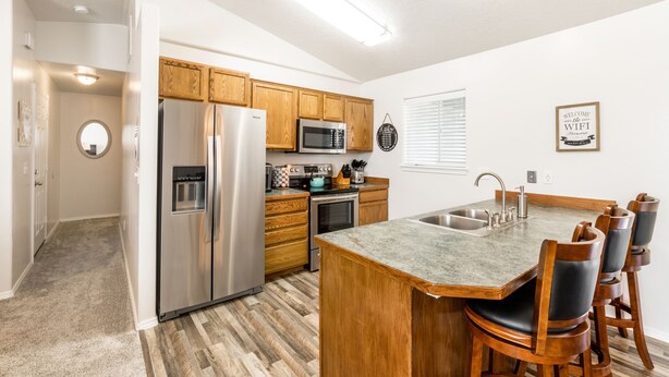 Una cocina moderna con armarios de madera, electrodomésticos de acero inoxidable y una isla central con taburetes de bar.