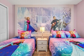 Una camera da letto con due letti, un comodino e un murale raffigurante personaggi animati.