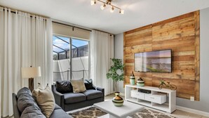 Ein modernes Wohnzimmer mit Sofa, Couchtisch, Fernseher und Holzwandverkleidung.