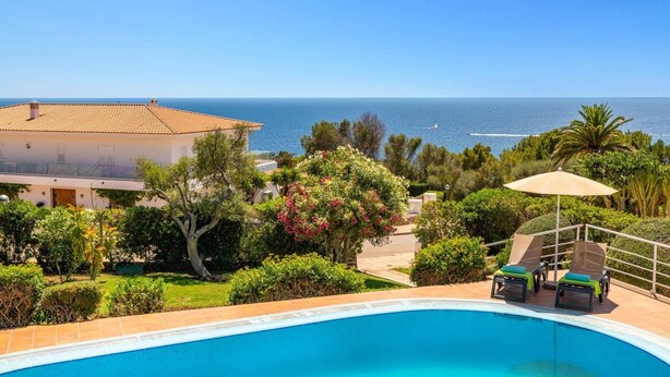 A poolside view with a clear view of the sea and a building with a tiled roof. - Villa Gecko by Villa Plus (Sant Tomas)