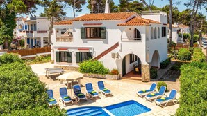 A two-story building with a swimming pool and lounge chairs.