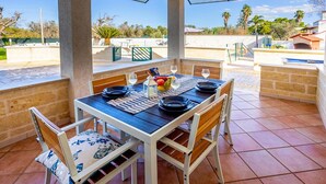 Une terrasse extérieure avec une table dressée pour deux personnes, entourée de chaises, et offrant une vue sur le paysage.