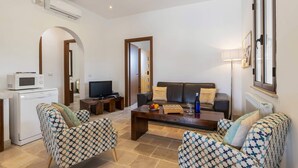 Una sala de estar con un sofá, dos sillones estampados, una mesa de centro, un televisor y un microondas.