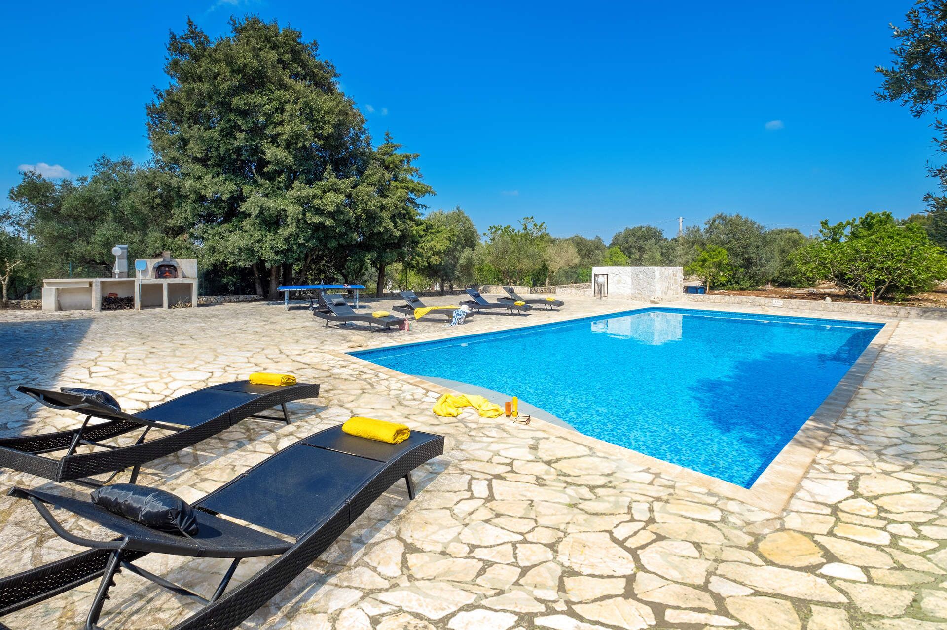 Area piscina con lettini e solarium in pietra.