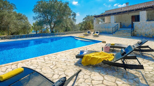 Una piscina con sillas de descanso y un edificio de piedra al fondo.