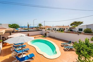 A residential area with a swimming pool, lounge chairs, and a view of the sea. - Villa Quimera by Villa Plus (Cala en Porter)