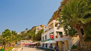 A coastal street with outdoor seating at a cafe, a bar, and a restaurant. - Villa Karenessa by Villa Plus (Cala en Porter)