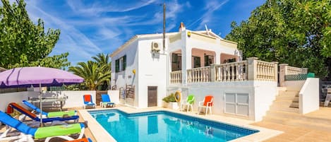 Relax by the pool surrounded by comfortable lounge chairs and a shaded area.