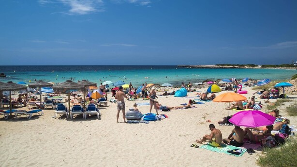 Une plage avec des transats, des parasols et des gens qui se détendent.