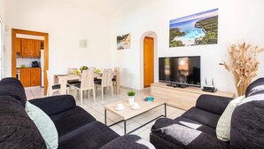 Un salon moderne avec un téléviseur, un canapé et un coin repas.