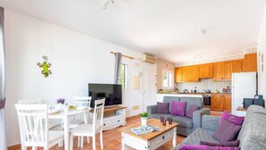 A compact living space with a dining area, a sofa set, and a kitchen.