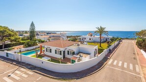 A coastal residential area with white buildings, a swimming pool, and a clear view of the sea. - Villa Ondinas by Villa Plus (Ciutadella de Menorca)
