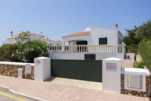 A villa with a gated entrance, a balcony, and a stone wall.