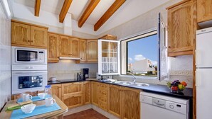 Una cocina con armarios de madera, una ventana, un lavamanos, un microondas, un horno y un lavavajillas.