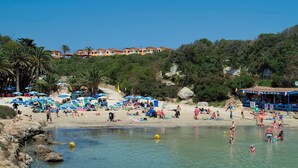 A beach with numerous umbrellas, people, and a clear sky. - Villa Solana by Villa Plus (Ciutadella de Menorca)