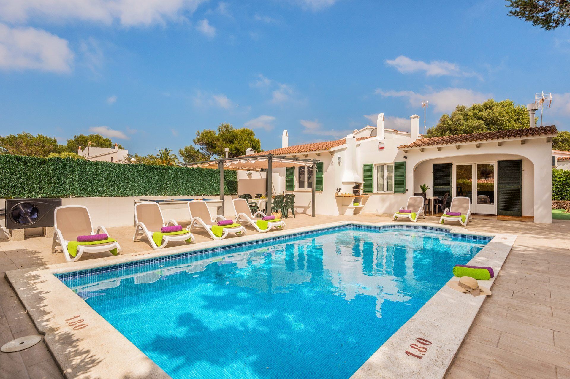 Una piscina con sillones de descanso y un área de patio.