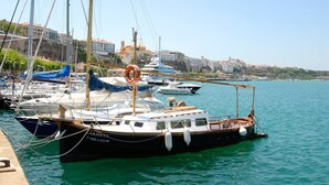 Un port de plaisance avec plusieurs bateaux amarrés, une bouée de sauvetage attachée à un bateau, et des bâtiments en arrière-plan.
