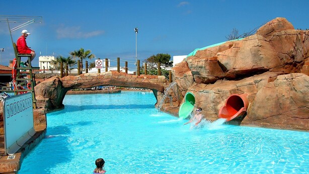 A pool area with a water slide, a lifeguard stand, and a no diving sign. - Villa Pomelo by Villa Plus (Ciutadella de Menorca)