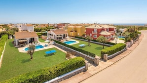 A residential area with multiple houses, a swimming pool, and a well-maintained lawn. - Villa Pomelo by Villa Plus (Ciutadella de Menorca)