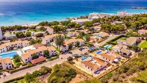 Ilmakuva rannikkoalueen asuinalueesta, jossa on huviloita, mukaan lukien Villa Santo Grande ja Villa Santo Tomas. Alueella on Välimeren arkkitehtuurille tyypillisiä rakennuksia, uima-altaita ja ranta.