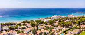 Vue aérienne d’un quartier résidentiel en bord de mer, avec des villas, dont la Villa Santo Grande et la Villa Santo Tomas, caractérisé par une architecture méditerranéenne, des piscines et une plage.