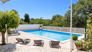 Una piscina con sillas de descanso y una zona sombreada.
