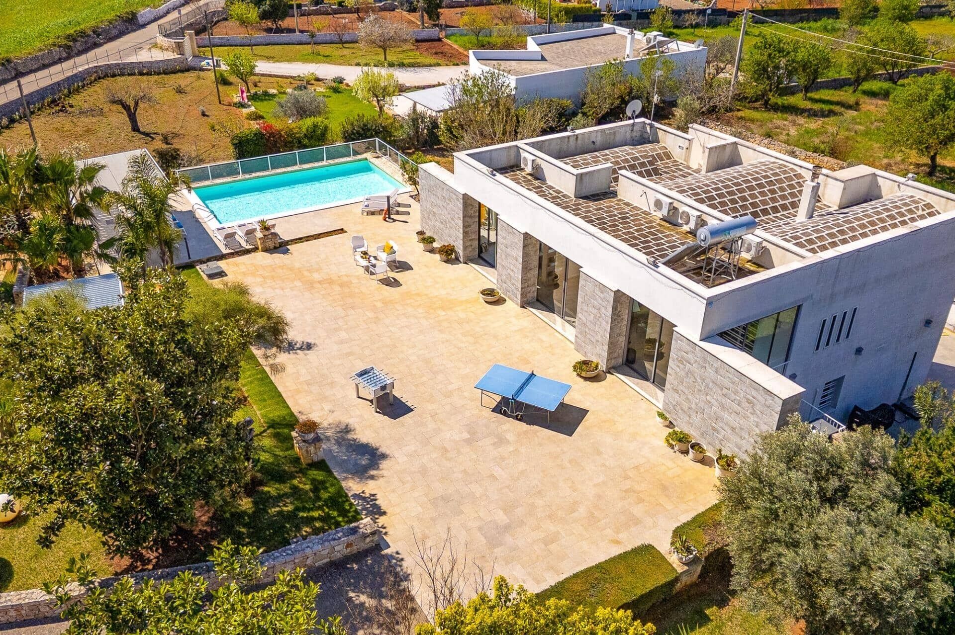 Una casa moderna con piscina, zona de estar exterior y un amplio patio.