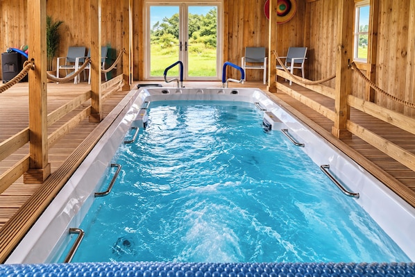 A hot tub with wooden railings and a view of greenery outside.