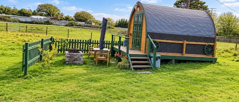 A small, single-story cabin with a porch, a table, and a bench.