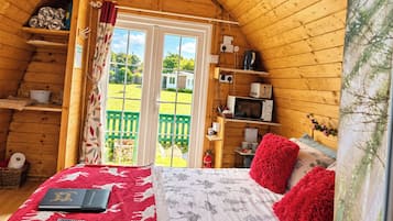 Una stanza accogliente con un letto, una televisione e vista su un giardino verde attraverso una porta.