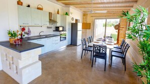 Una cocina amplia con electrodomésticos modernos, un comedor con mesa preparada para cuatro personas y vistas al exterior.