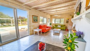 Amplia sala de estar con vista a la piscina, chimenea y comedor con mesa y sillas.