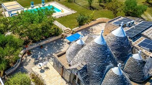 A rooftop pool with a blue deck, surrounded by stone structures and solar panels. - Villa Trullo Bozalice by Villa Plus (Martina Franca)