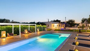 A swimming pool with lounge chairs and a covered seating area.