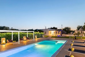 Une piscine avec des chaises longues et un espace de détente abrité.