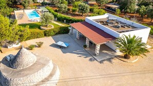 A modern villa with a swimming pool, a covered patio, and a stone structure.