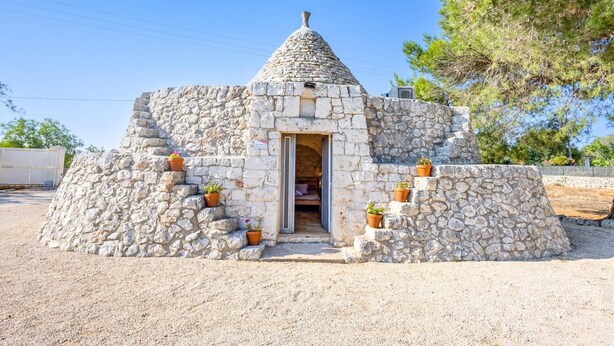 A stone structure with a conical roof, a door, and steps leading up to it.