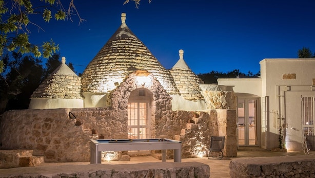 Um edifício com fachada de pedra e vários telhados cônicos, mesa de bilhar e uma porta que dá para um espaço interno.