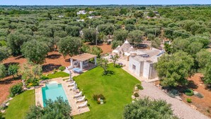 Vista aérea de uma propriedade com piscina, área de estar ao ar livre e um edifício de pedra com telhado de azulejos.