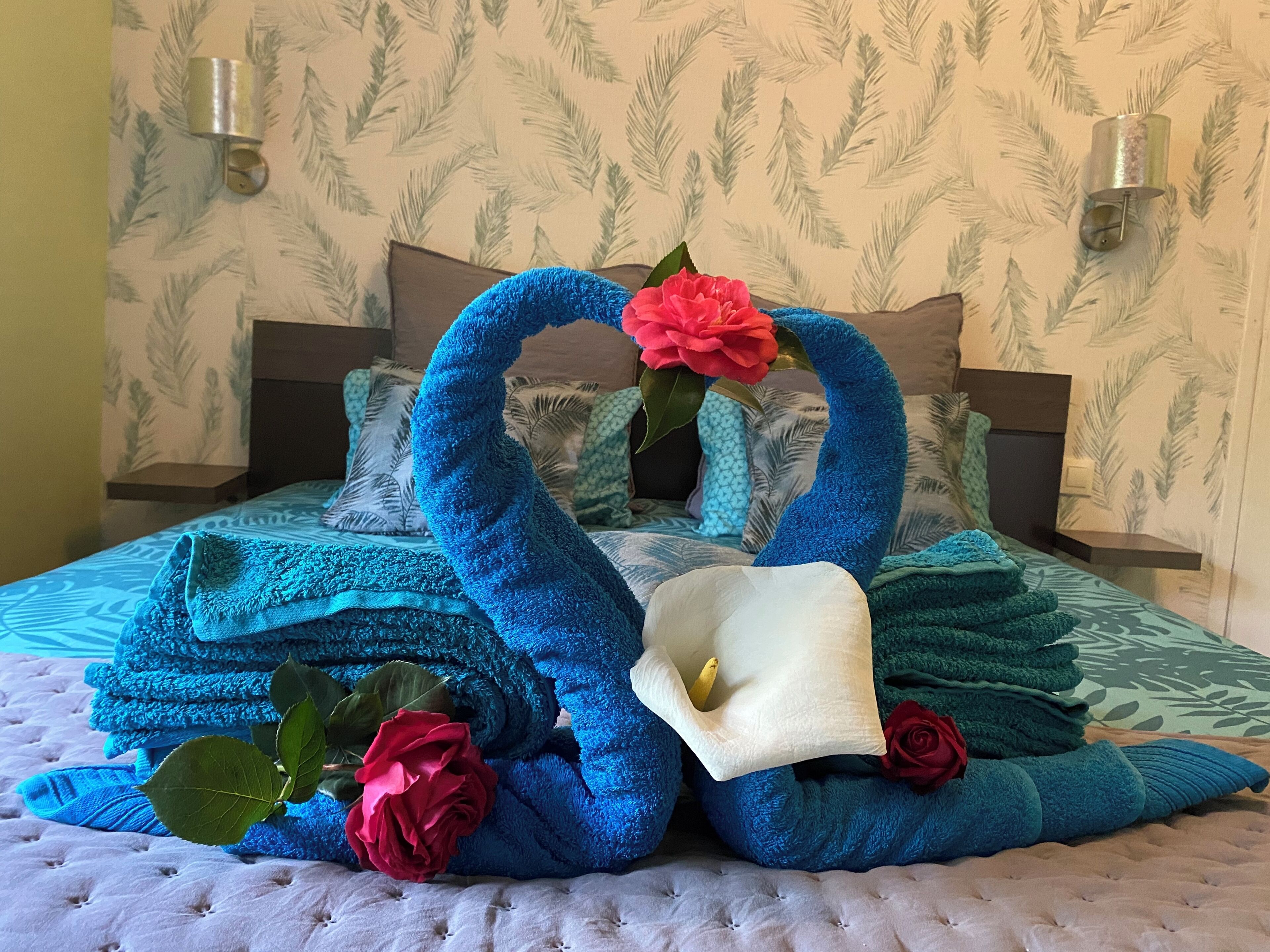 Ein Bett mit einer blau-weißen Bettdecke, einem blaufarbenen schwanenförmigen Kissen und einem weißen Schwanenkissen.