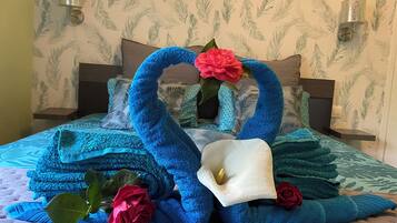 Ein Bett mit einer blau-weißen Bettdecke, einem blaufarbenen schwanenförmigen Kissen und einem weißen Schwanenkissen.