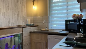 A modern kitchen with a built-in fish tank, wooden cabinets, a microwave, and a window with blinds.