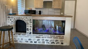 A kitchen with a stone island, a built-in fish tank, wooden cabinets, and a microwave.