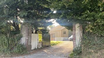 A gated entrance to a building with a brick wall and a metal gate, surrounded by dense foliage.