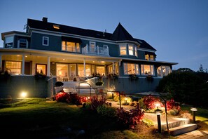 A two-story house with a balcony, a front porch, and a well-lit garden area. - Cape Arundel Inn and Resort (Kennebunkport)