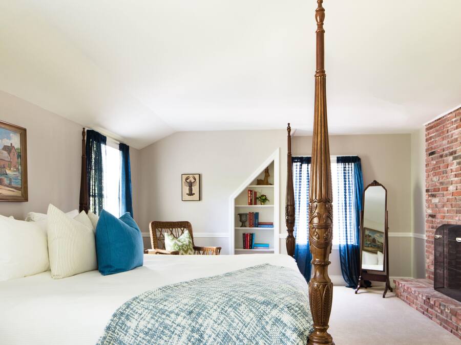 Una camera da letto con un letto a baldacchino, una libreria, uno specchio e un muro in mattoni.