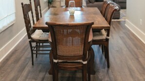 Een eethoek met een houten tafel en stoelen, een kroonluchter en een plant.