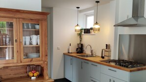A modern kitchen with white cabinets, a wooden countertop, a gas stove, and hanging pendant lights. - Beautiful detached house in an oasis of calm, close to beach and sea. (Koudekerke)